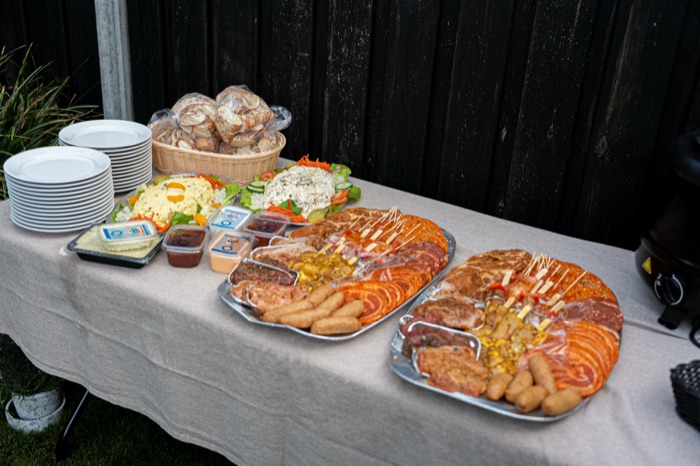 Complete BBQ-schotels met salades, stokbrood en sauzen op tafel