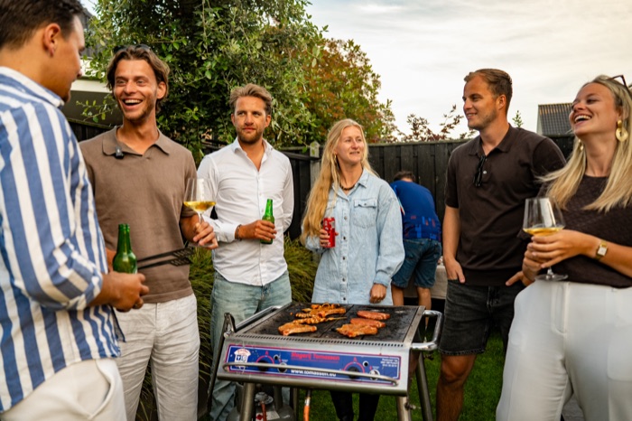 Gezelschap met een drankje rondom de barbecue